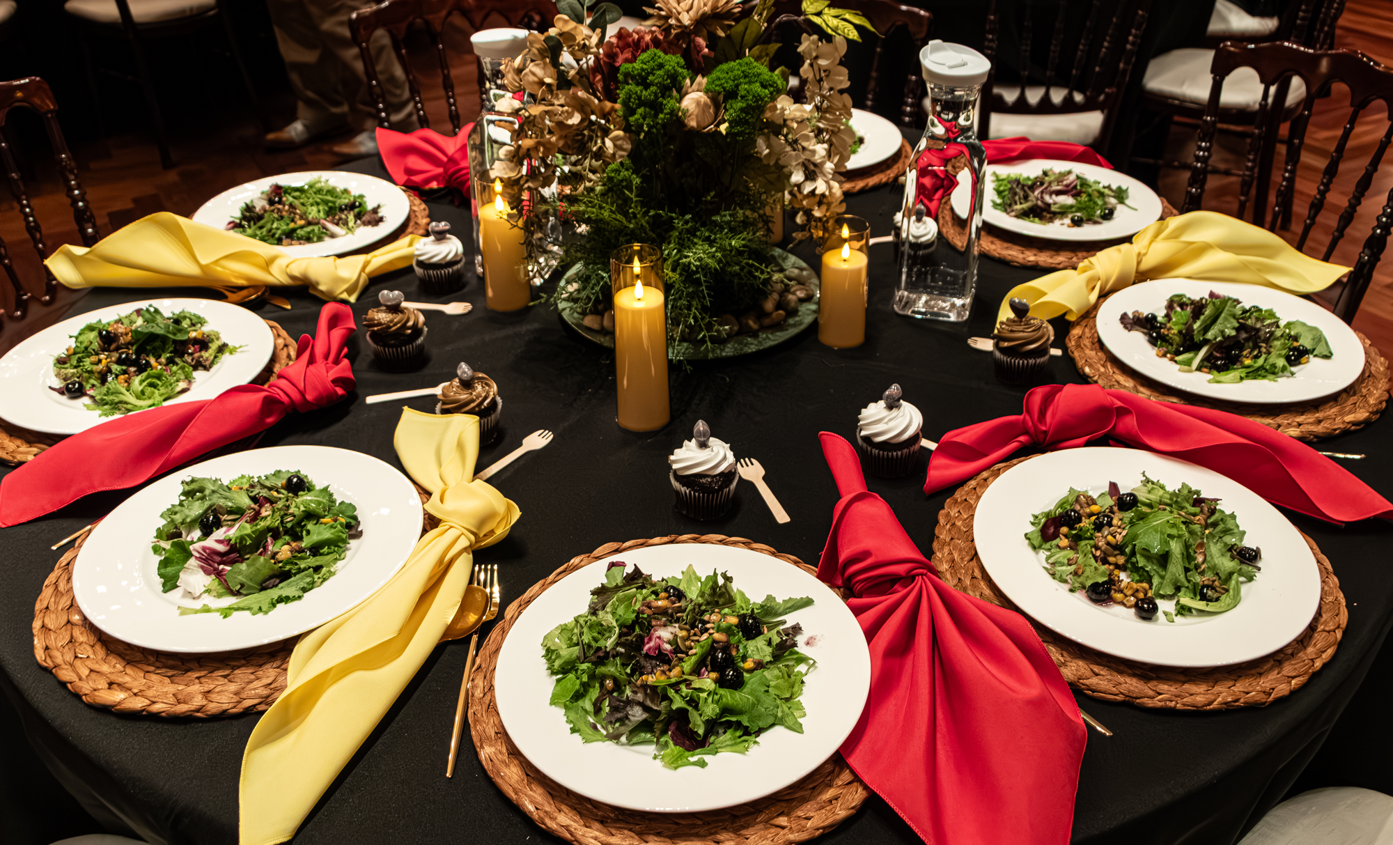 An elegantly prepared gala dinner table at the Newberry Library, with woven chargers, candlelight, flowers and plated salads.